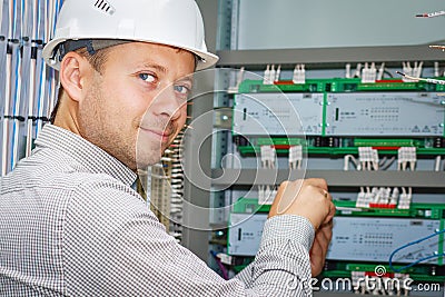 Engineer tests industrial electrical circuits in control terminal box. Electrician adjusts electric equipment in automation panel. Stock Photo