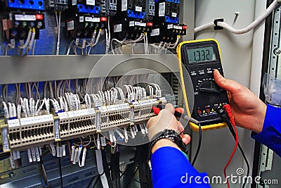 Engineer tests industrial electrical circuits with a multimeter in the control terminal box Stock Photo