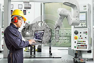 Engineer using laptop computer control automatic robotic hand with CNC machine in automotive industry, Smart factory concept Stock Photo