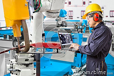 Engineer using laptop computer maintenance robot grip automotive workpiece position, Smart factory concept Stock Photo