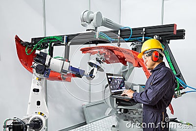 Engineer using laptop computer maintenance robot grip automotive workpiece, Smart factory concept Stock Photo