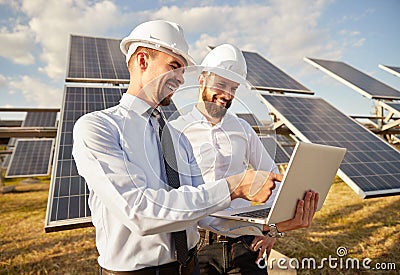 Engineer using laptop near photovoltaic panels producing renewable solar energy Stock Photo