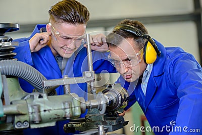 Engineer using machine apprentice with fingers in ears Stock Photo