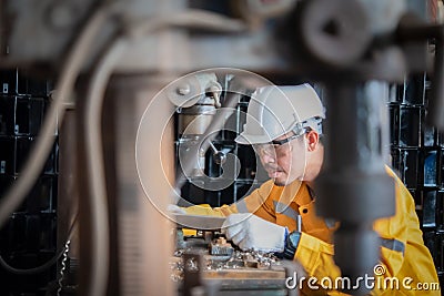 Engineer wearing yellow work clothes white hardhat and wear glove working machine in industry Stock Photo