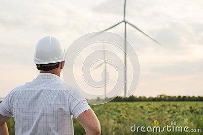 Engineer in a wind turbine. A man in a helmet supervises the operation of the electric windmills. Ecology and renewable energy Stock Photo