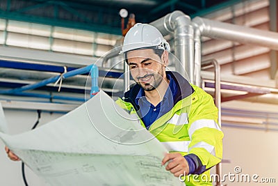 Engineer worker with floor plan blueprint paper of machine service instruction working in factory Stock Photo