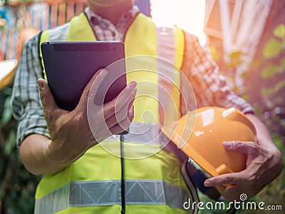 Engineering man standing with yellow safety helmet and holding tablet, work concept Stock Photo