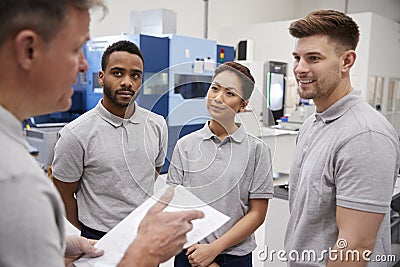 Engineering Team Meeting On Factory Floor Of Busy Workshop Stock Photo