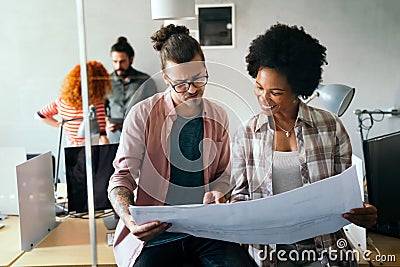 Engineers helping design work on blueprints, collaborate on structural analyzing of project types. Stock Photo