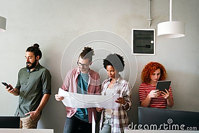 Engineers helping design work on blueprints, collaborate on structural analyzing of project types. Stock Photo