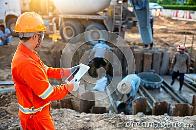 Engineers inspect the pouring of concrete with tablet Stock Photo