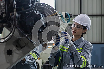 Engineers woman maintenance robotic arm. Female technician industrial checking robot machine. Futuristic industry production Stock Photo