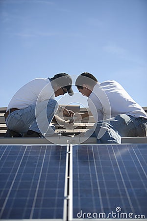 Engineers Working On Solar Panelling At Rooftop Stock Photo