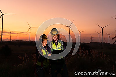 Engineers working on wind turbines farm at sunset, Stock Photo