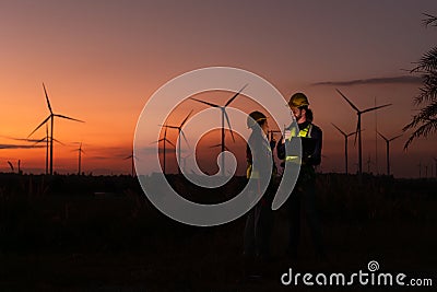 Engineers working on wind turbines farm at sunset, Stock Photo