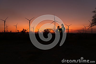 Engineers working on wind turbines farm at sunset, Stock Photo