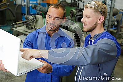 engineers in workshop looking at laptop Stock Photo