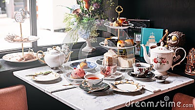 English afternoon tea set including hot tea, pastry, scones, sandwiches and mini pies on marble top table Stock Photo