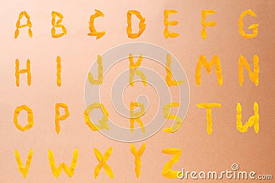 English alphabet of yellow letters made of sunflower petals on a beige shiny background Stock Photo