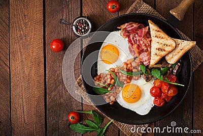 English breakfast - fried egg, beans, tomatoes, mushrooms, bacon and toast. Stock Photo