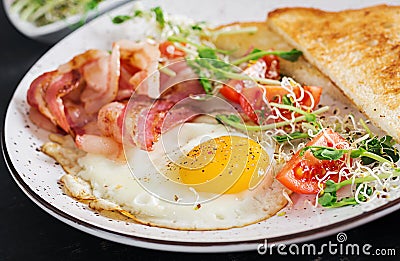 English breakfast - toast, egg, bacon and tomatoes and microgreens salad Stock Photo