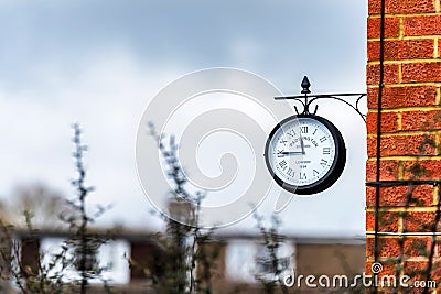 English brick house corner with dangling retro clock with Paddington Station London text on it Stock Photo