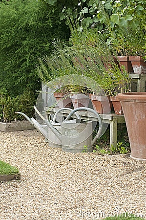 Watering cans and flower pots in English cottage garden.