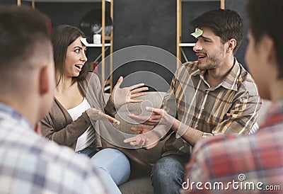 Engrossed couple playing forehead detective game with friends Stock Photo