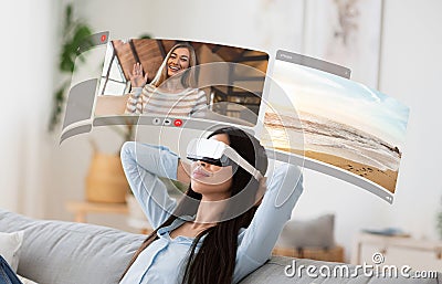 Young asian woman dives into virtual reality for video chats from home, relaxing on sofa with digital screens Stock Photo