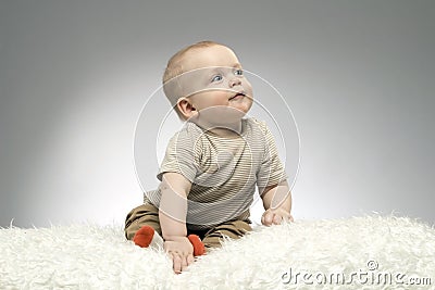 Enigmatic baby is looking away on the grey background Stock Photo