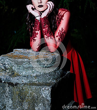 Enigmatic Gothic Beauty - Slender Woman in Red Dress Amidst Dark Forest Stock Photo