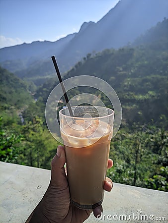 Enjoy the beauty of the Rahtawu Kudus mountains while drinking a glass of iced coffee Stock Photo