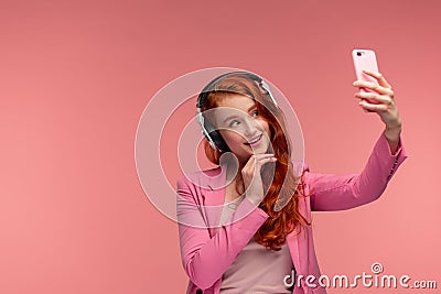 Enjoy listening to music. Beautiful young redhead woman with headphones listening music and making selfie. Funny smiling Stock Photo
