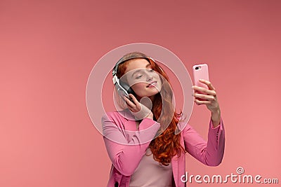 Enjoy listening to music. Beautiful young redhead woman with headphones listening music and making selfie. Funny smiling Stock Photo