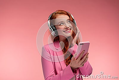 Enjoy listening to music. Beautiful young redhead woman with headphones listening music on smart phone using music app Stock Photo