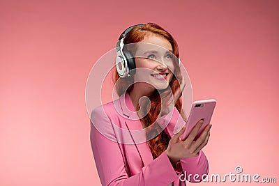 Enjoy listening to music. Beautiful young redhead woman with headphones listening music on smart phone using music app Stock Photo