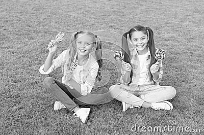 Enjoy these lollipops with taste sensation. Happy children hold lollipops green grass. Eating large swirl lollipops on Stock Photo