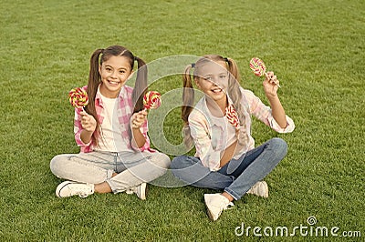 Enjoy these lollipops with taste sensation. Happy children hold lollipops green grass. Eating large swirl lollipops on Stock Photo