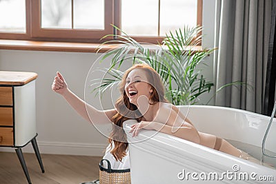 Pretty naked woman enjoying a bath and looking contented Stock Photo