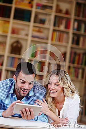 Enjoying a bit of light-hearted surfing. a young couple sitting at home using a digital tablet. Stock Photo