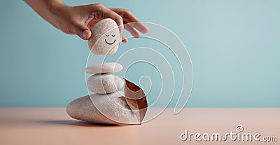 Enjoying Life Concept. Harmony and Positive Mind. Hand Setting Natural Pebble Stone with Smiling Face Cartoon to Balance on Beach Stock Photo