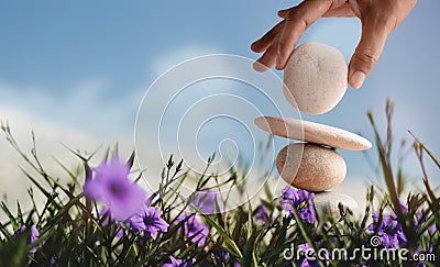 Enjoying Life Concept. Harmony and Positive Mind. Hand Setting Natural Pebble Stone with Smiling Face Cartoon to Balance Flower Stock Photo