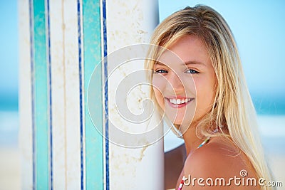 Enjoying the moment. Portrait of a pretty blonde with her surfboard on the beach. Stock Photo