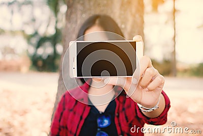 Enjoying moment woman using smartphone sitting under the big tree on park Stock Photo