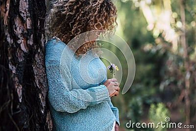 Enjoying the nature - Young woman care a little coloured fresh flower in the wood - concept of save the planet and care the earth Stock Photo