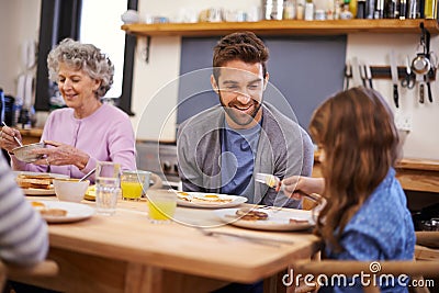 Enjoying a scrumptious breakfast together. a family eating breakfast around the kitchen table. Stock Photo