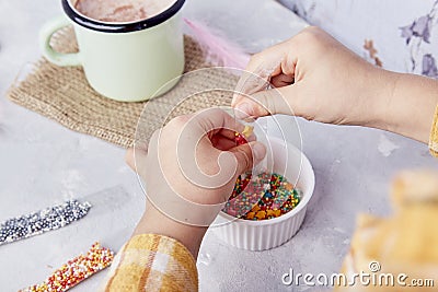 Enjoying the taste of Easter traditions as a child sprinkles cookies for a festive vibe Stock Photo