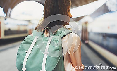 Enjoying travel. Young woman waiting on the station platform with backpack on background electric train. Tourist plan route Stock Photo