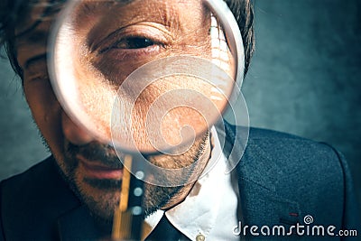 Enlarged eye of tax inspector looking through magnifying glass Stock Photo