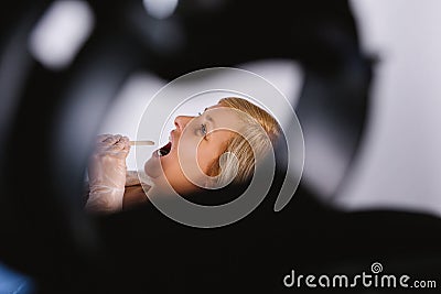 Enlarged photo. The therapist's hands are checking the sore throat with a wooden scapula on an older woman. Stock Photo